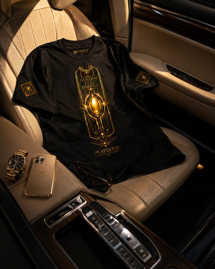 Black PEAFDOVE® Golden Egg Pressure Shirt arranged on the passenger seat of a luxury car with gold-toned accessories.